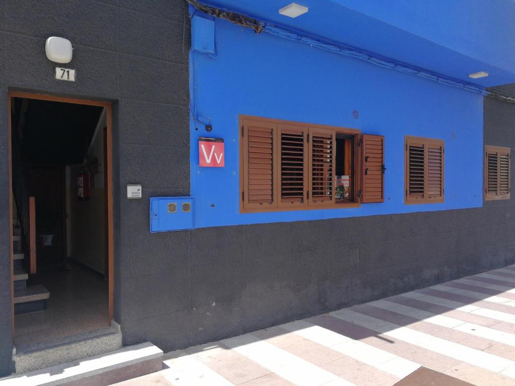 um edifício azul com persianas castanhas e um sinal nele em Casa Mar Azul em Arinaga