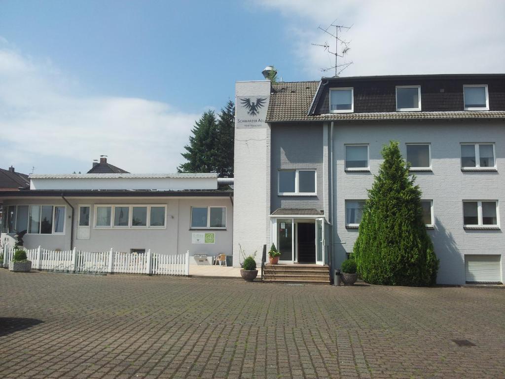 une maison blanche avec une clôture blanche devant elle dans l'établissement Hotel Schwarzer Adler, à Moers