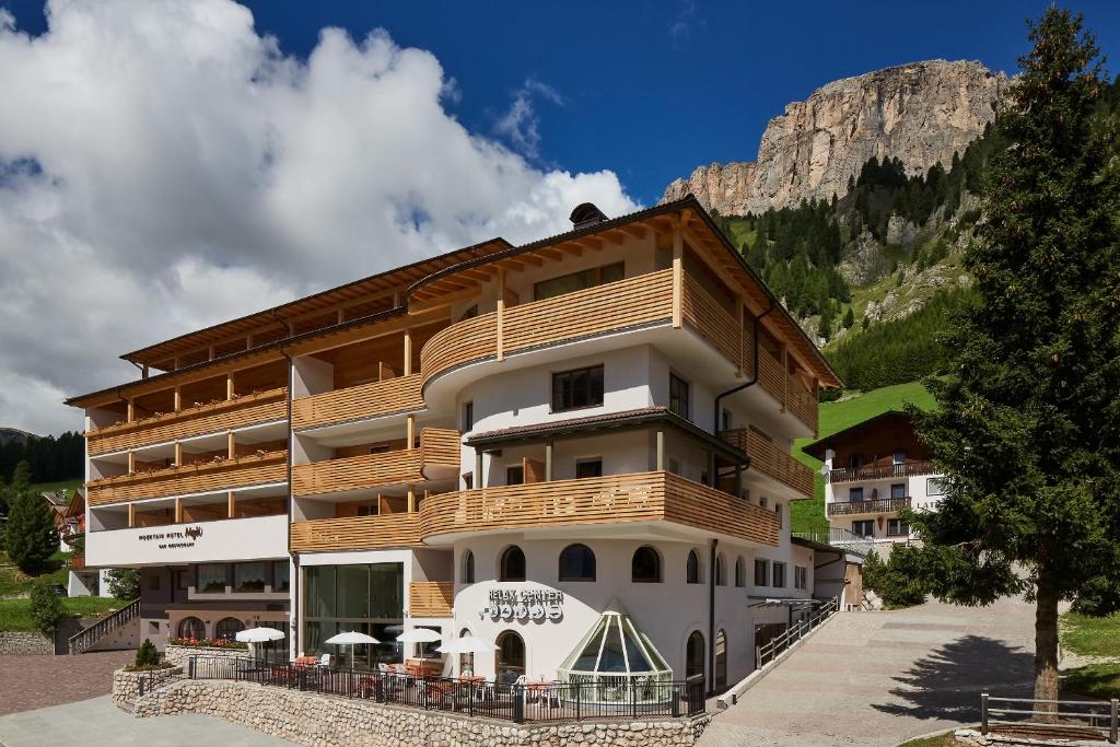 a large building with a mountain in the background at Mountain Hotel Mezdì in Colfosco