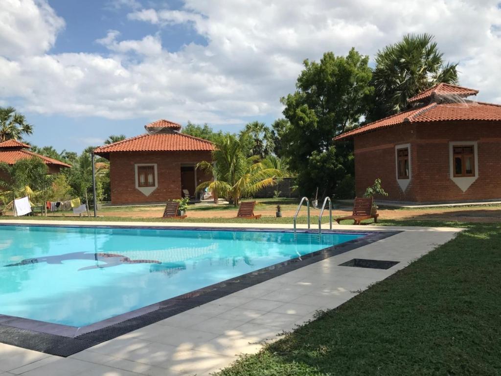 a swimming pool in front of a house at Aki Villa in Pasikuda