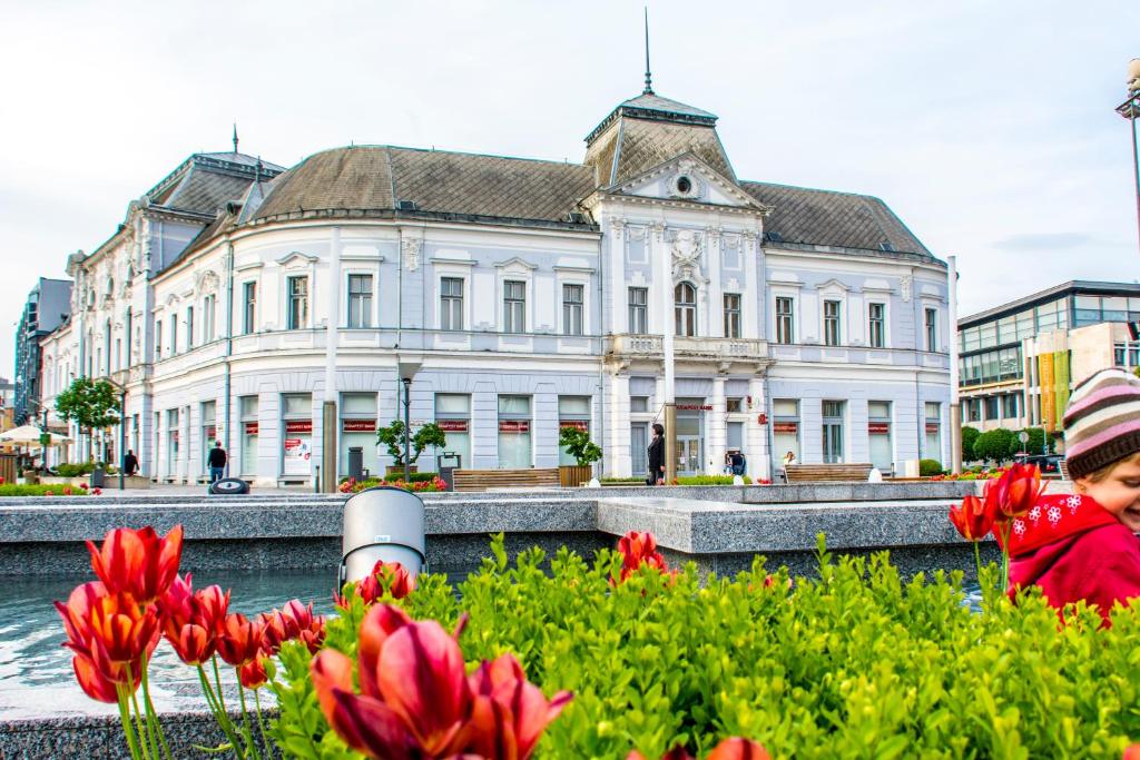 un grand bâtiment blanc avec des fleurs rouges devant lui dans l'établissement Korona Hotel, à Nyíregyháza