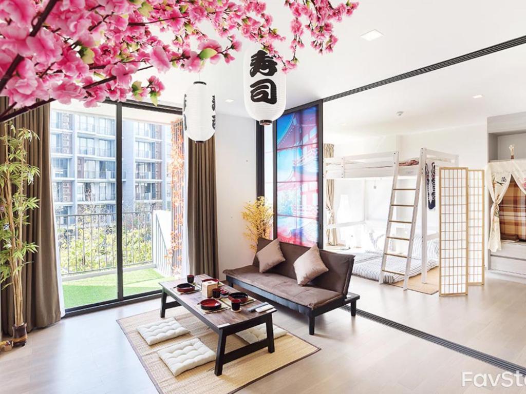una sala de estar con sofá y un árbol con flores rosas en Japan Room 104-B KhaoYai at TVL เขาใหญ่, en Phayayen
