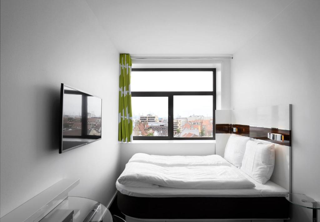 a white bedroom with a bed and a window at Wakeup - Aarhus in Aarhus