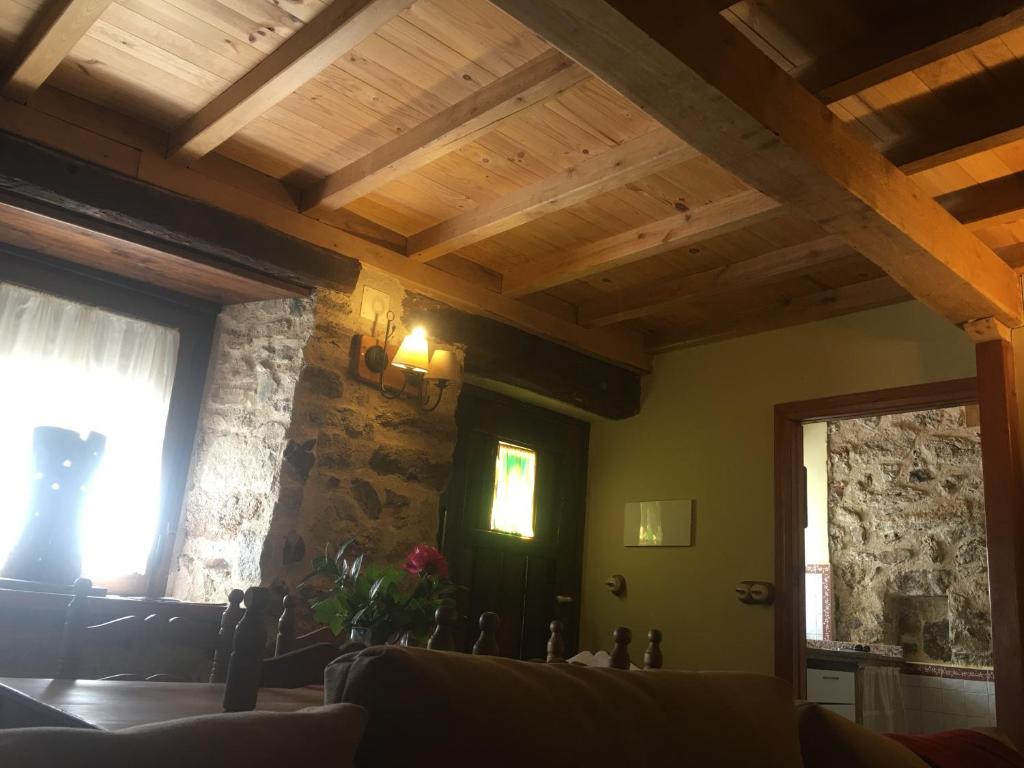 a living room with wooden ceilings and a stone wall at Casa Rural Jim Morrison in Linares de Riofrío