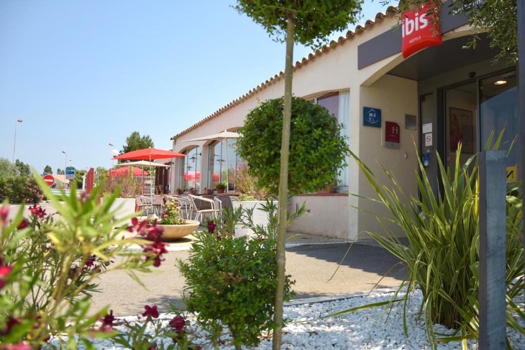un bâtiment avec des fleurs et des plantes à l'extérieur dans l'établissement Hotel ibis Narbonne, à Narbonne