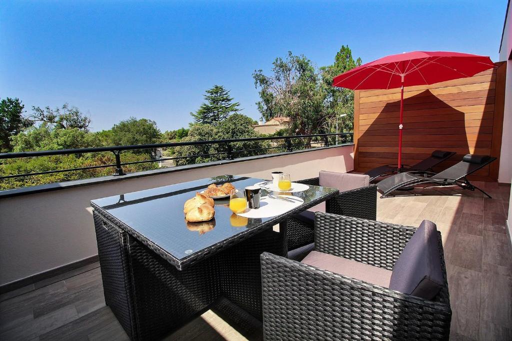 a table and chairs on a balcony with an umbrella at Residence ACQUA LINDA Porticcio in Porticcio