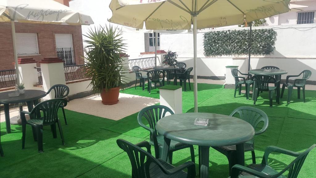 a patio with tables and chairs with green grass at Pension Yna Holiday in Málaga