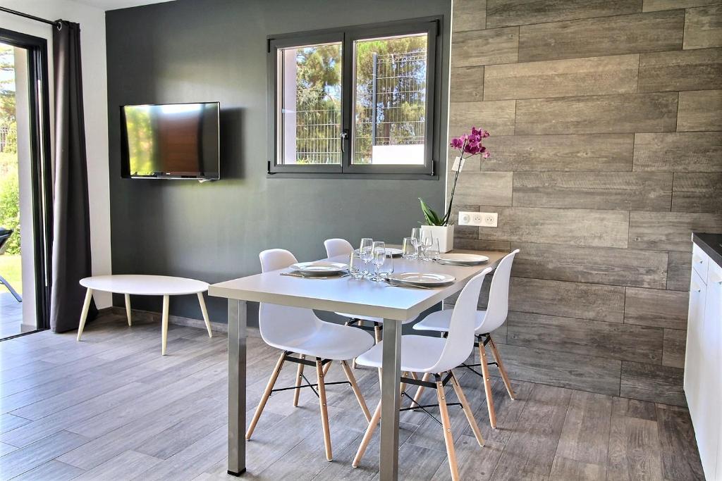 a dining room with a table and white chairs at Residence ACQUA LINDA Porticcio in Porticcio