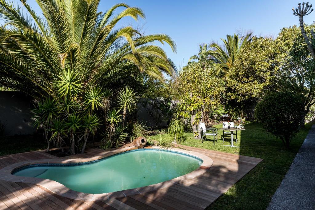 a swimming pool in a yard with palm trees at Le Petit Chateau Guest House in Durbanville