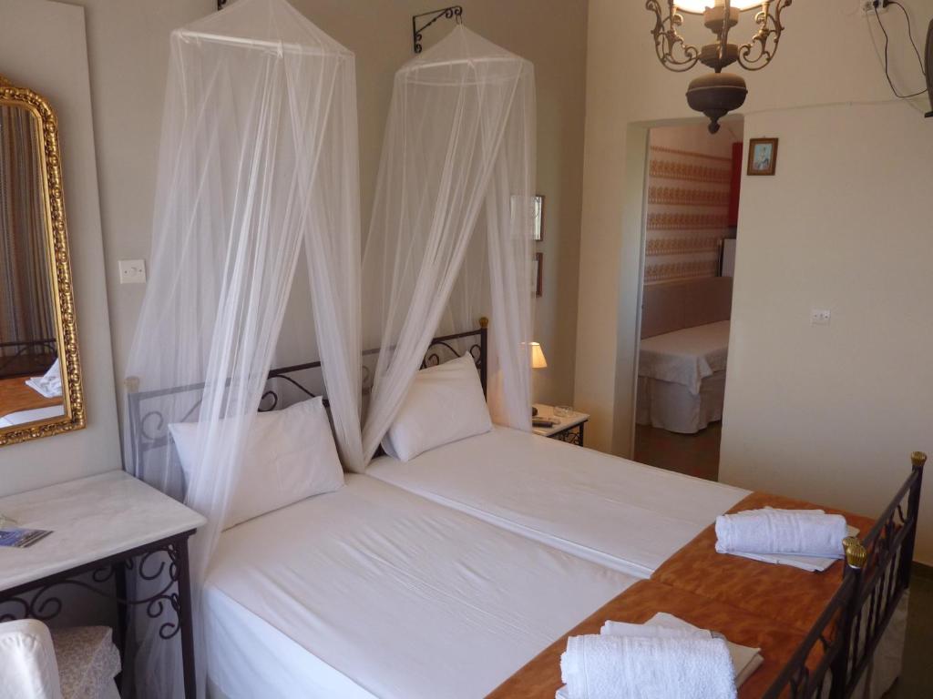 Schlafzimmer mit einem weißen Bett und Moskitonetzen in der Unterkunft Villa Niki in Serifos Chora