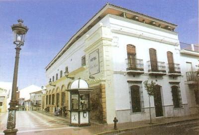 un edificio blanco con una luz de la calle delante de él en Plaza Chica en Cartaya