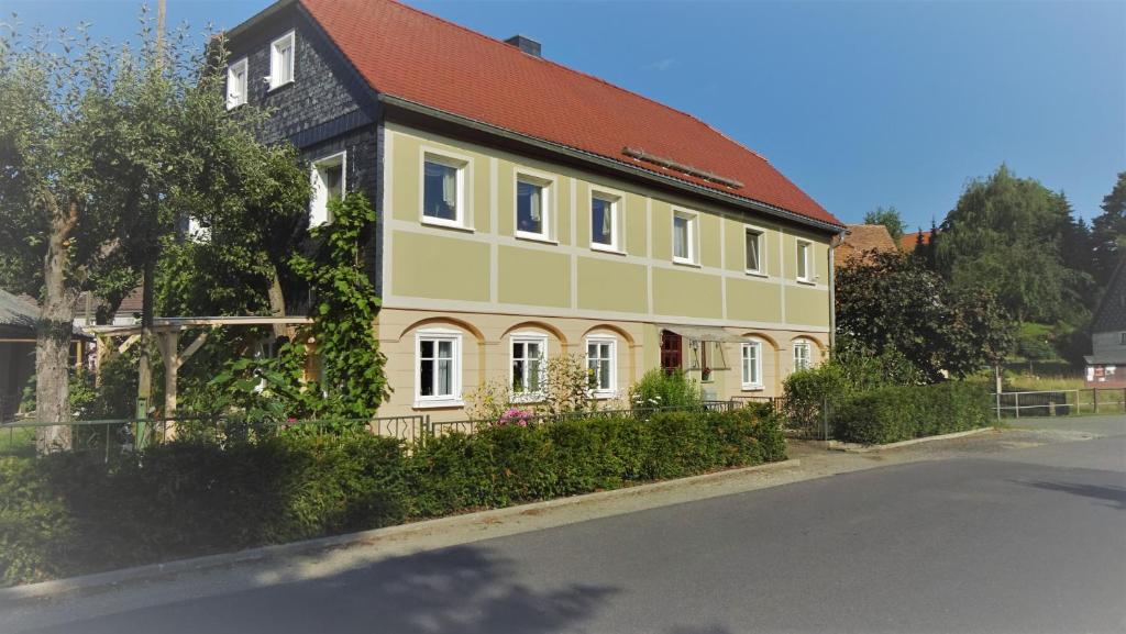 a yellow and green house with a red roof at Privatzimmer Lehmann in Kottmar