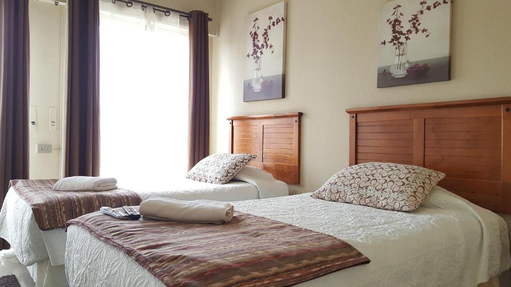a bedroom with two beds and a large window at Hostal Del Centro Talca in Talca