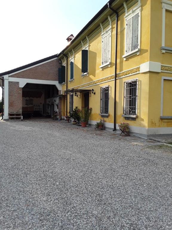 a yellow building with a driveway in front of it at Mu & Mu in Borgoforte
