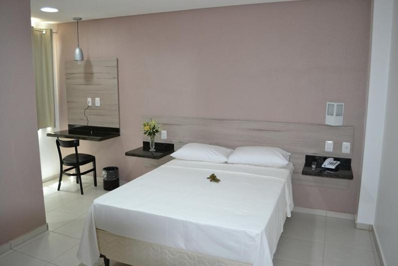 a bedroom with a large white bed and a desk at Hotel La Ville in Sousa