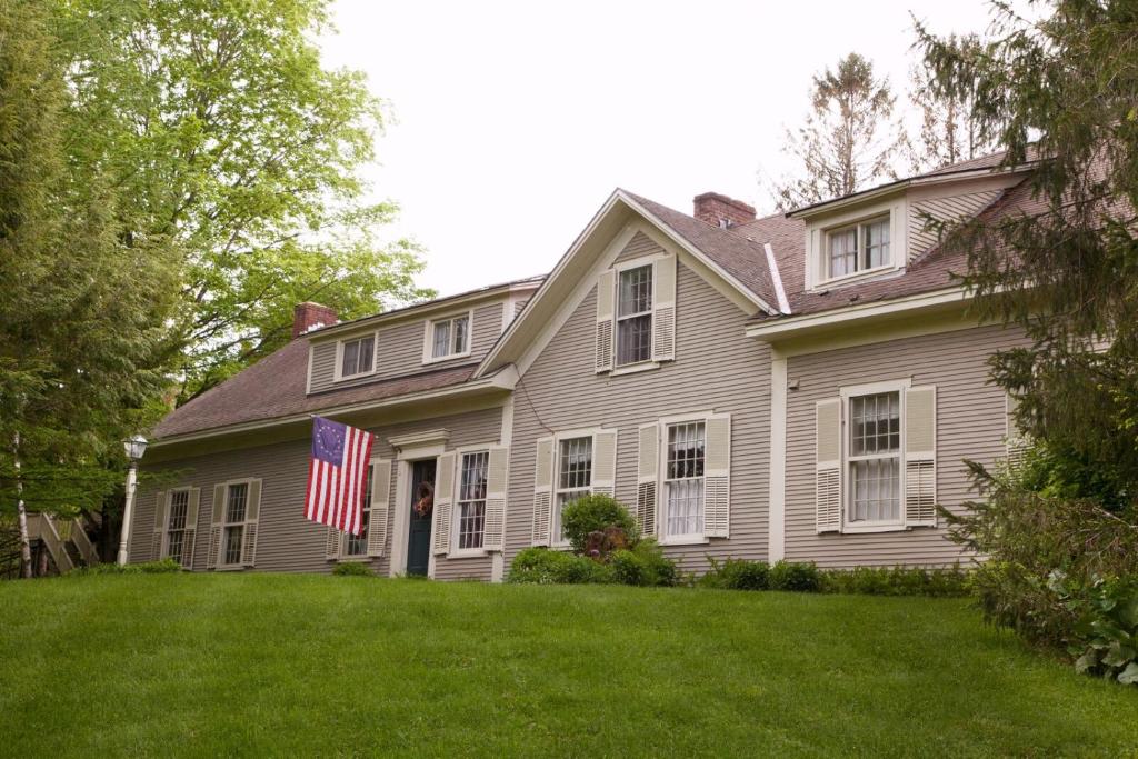 Ein weißes Haus mit amerikanischer Flagge im Hof in der Unterkunft The Featherbed Inn in Waitsfield