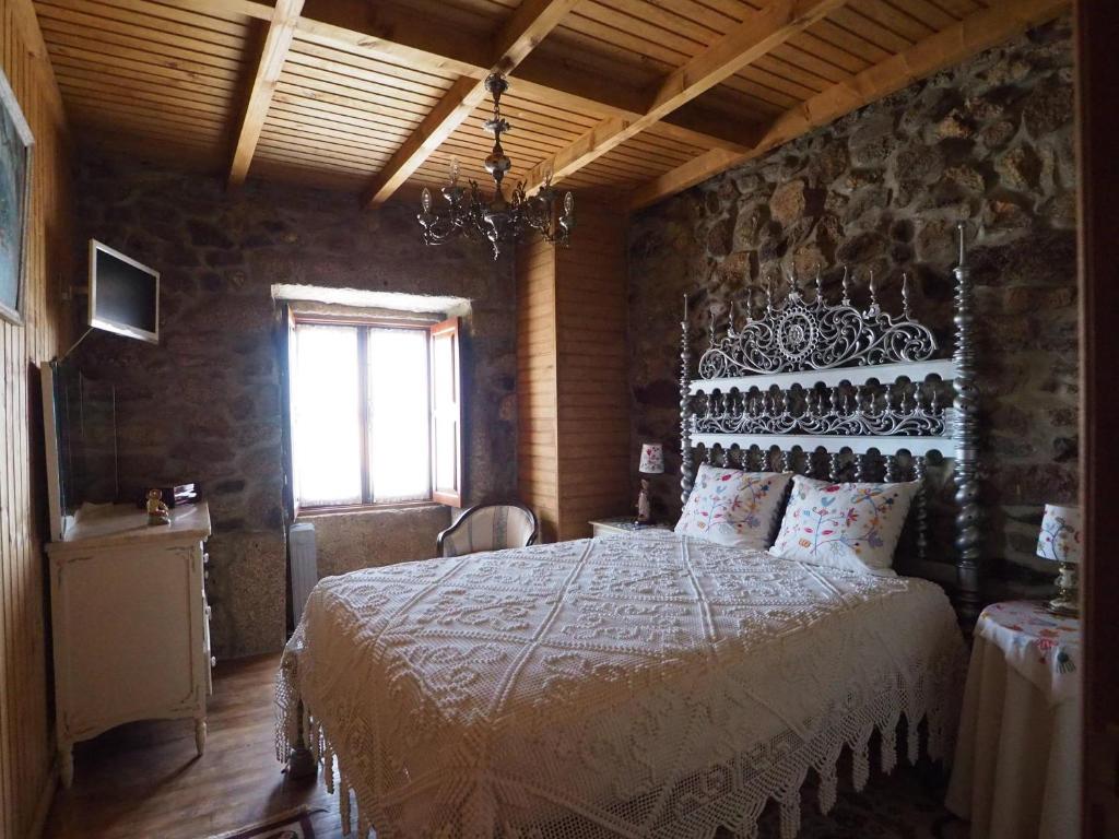 a bedroom with a large bed in a stone wall at Casa do Monge in Leomil
