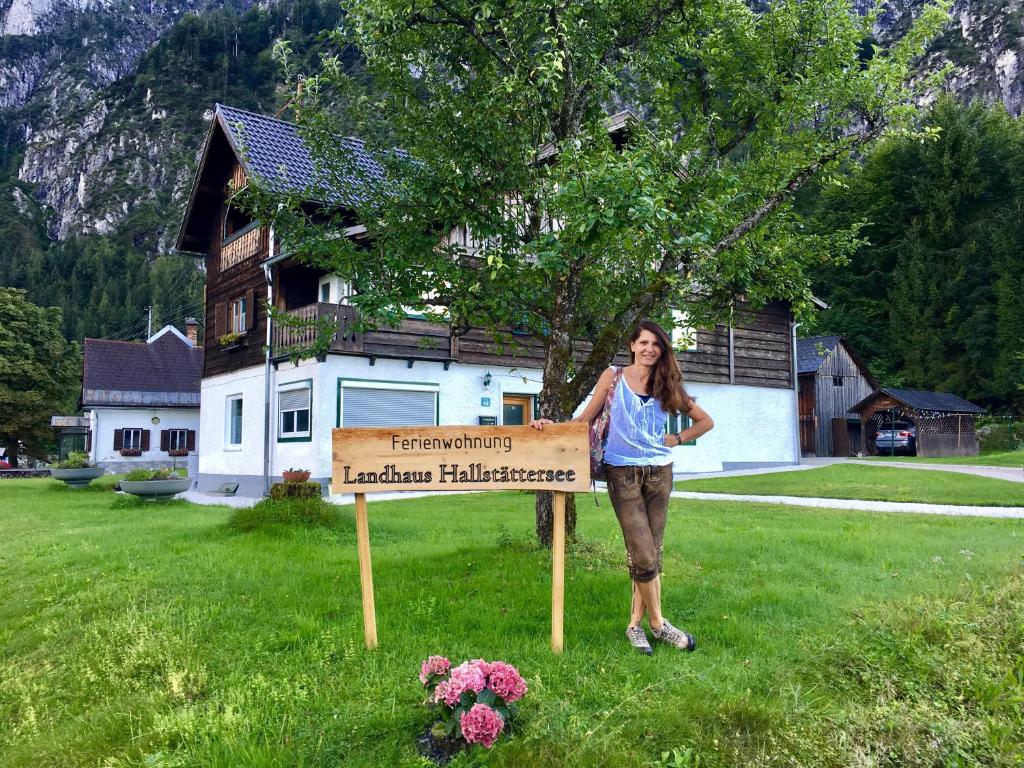 a woman standing next to a sign in a yard at Landhaus Hallstättersee in Bad Goisern
