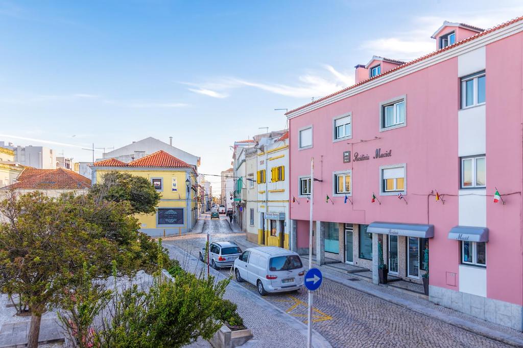 uma rua urbana com edifícios cor-de-rosa e amarelo em Best Houses Portugal Residence em Peniche