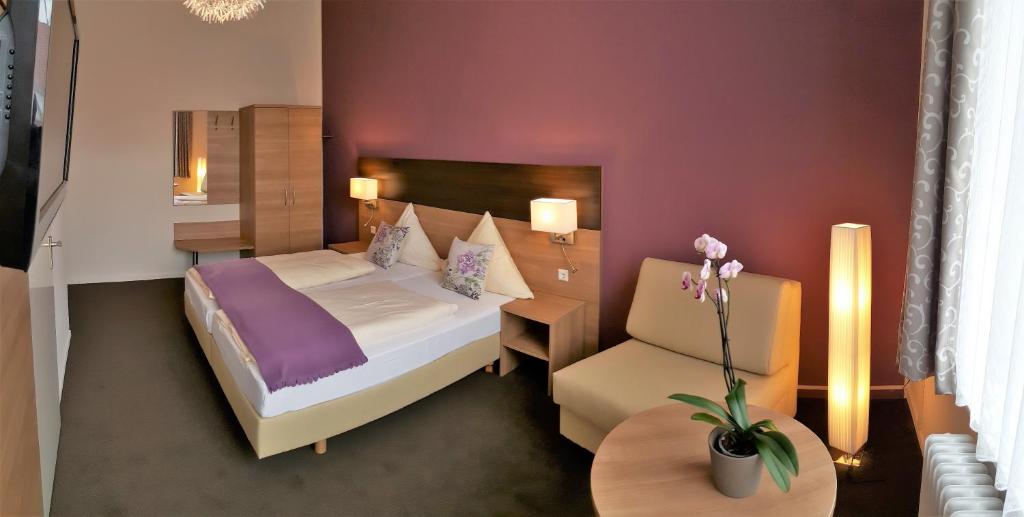 une chambre d'hôtel avec un lit et une chaise dans l'établissement Hotel Flora, à Hanovre