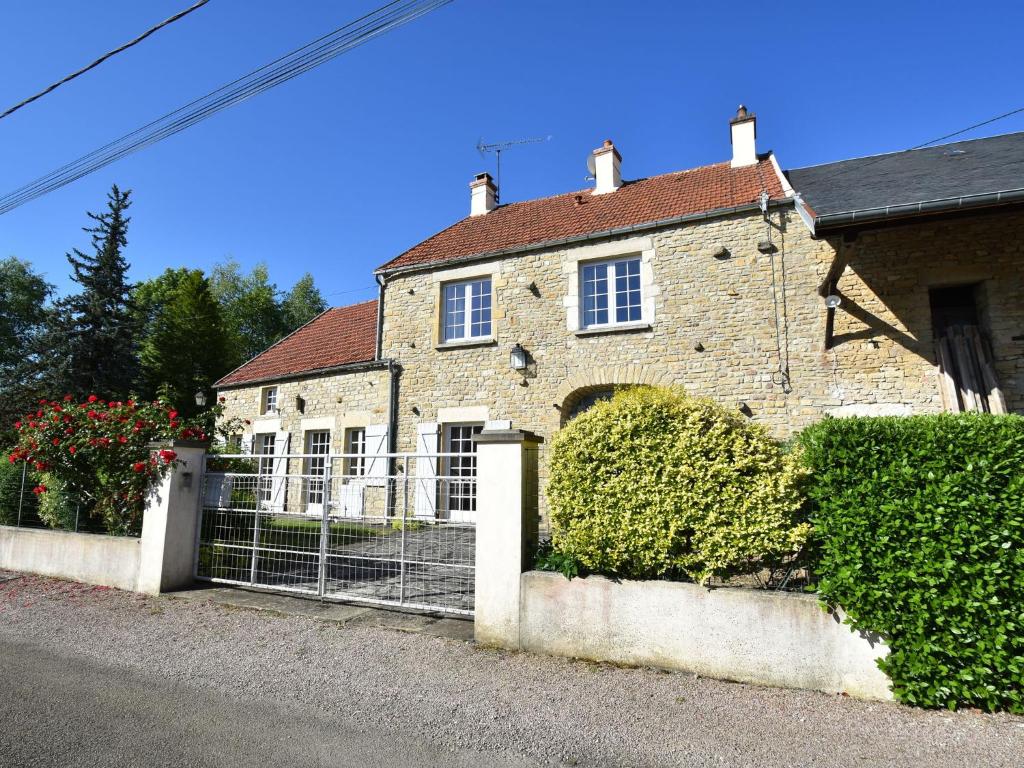 a brick house with a fence in front of it at Modern holiday home on the meadows in Vault-de-Lugny