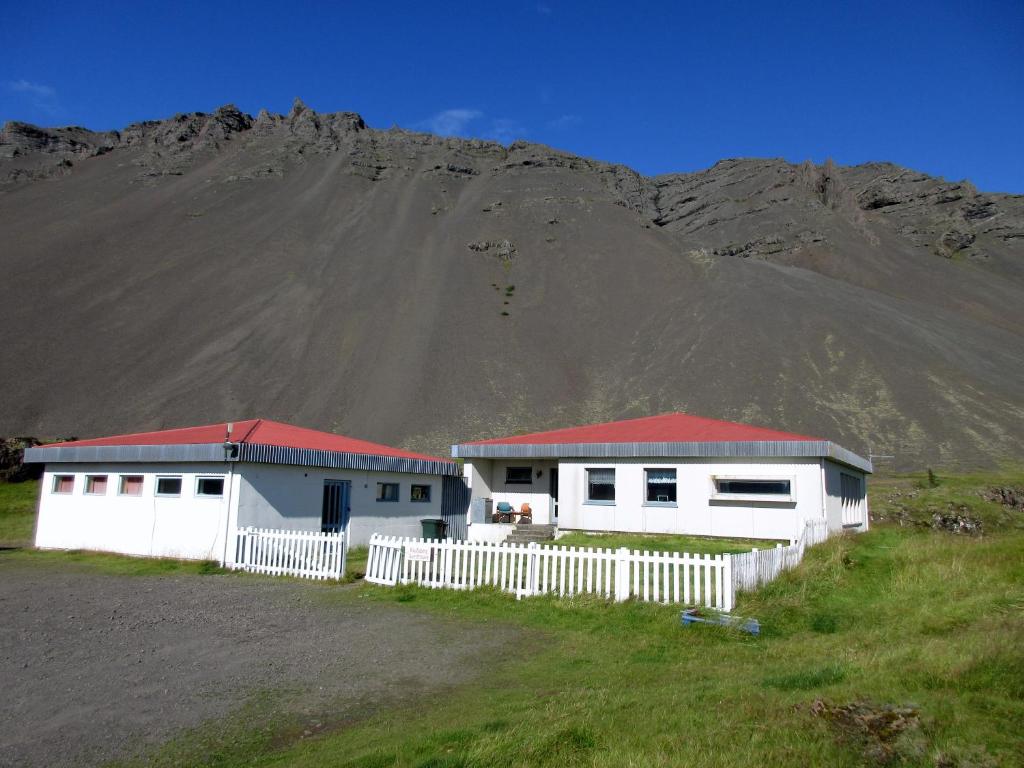 a white house with a blue roof and a white fence at Rauðaberg II in Raudaberg