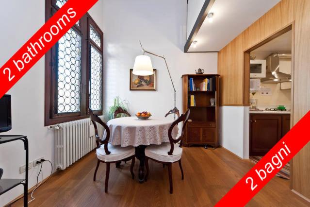 ヴェネツィアにあるAppartamento Accademia San Vioのテーブルと椅子2脚、キッチンが備わる客室です。
