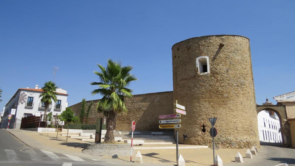 um edifício de tijolos alto com uma palmeira ao lado de uma rua em Hotel La Muralla em Zafra