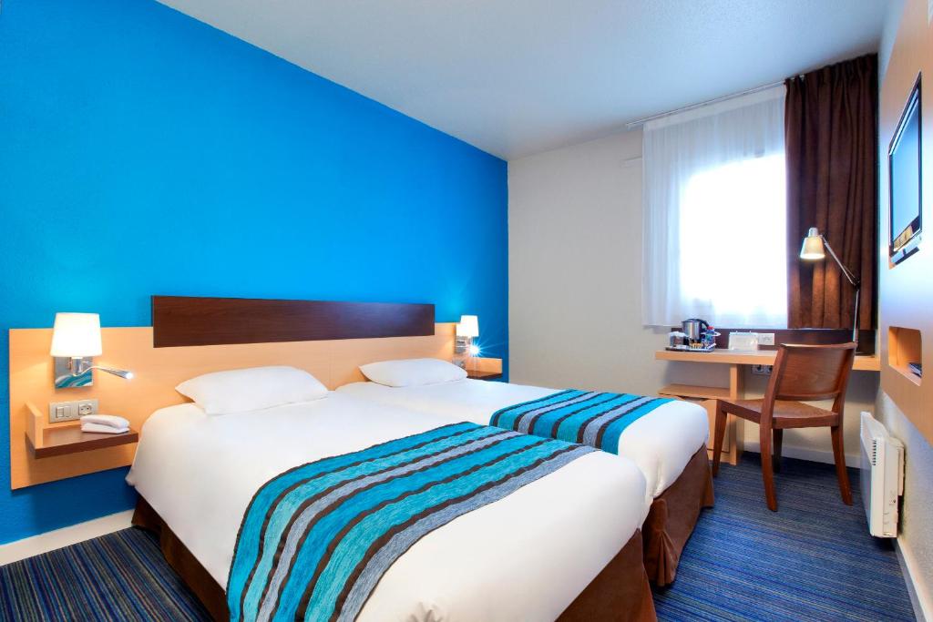 a hotel room with a large bed and a desk at Kyriad Viry-Chatillon in Viry-Châtillon
