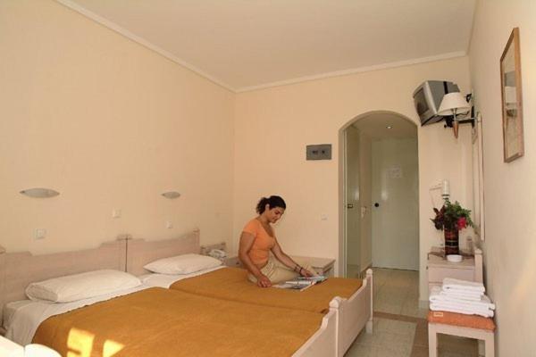 uma mulher em pé numa cama num quarto em Theonia Hotel em Cós