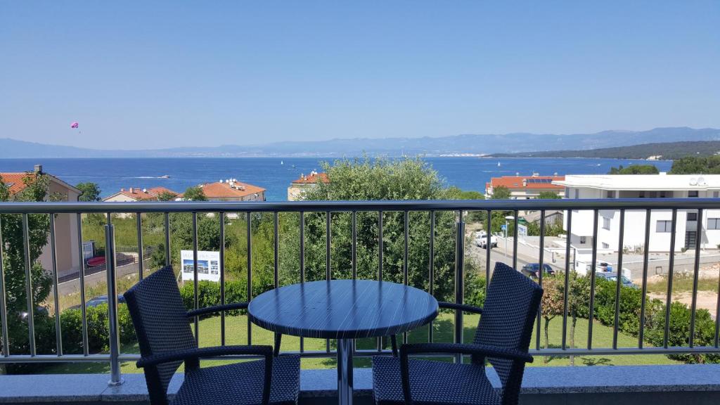 a table and chairs on a balcony with a view of the water at Villa Simfonija in Malinska
