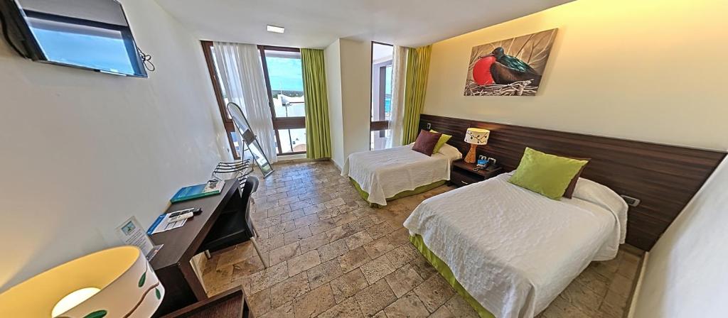 a small room with two beds and a television at Hotel Isla Sol by Solymar in Puerto Ayora