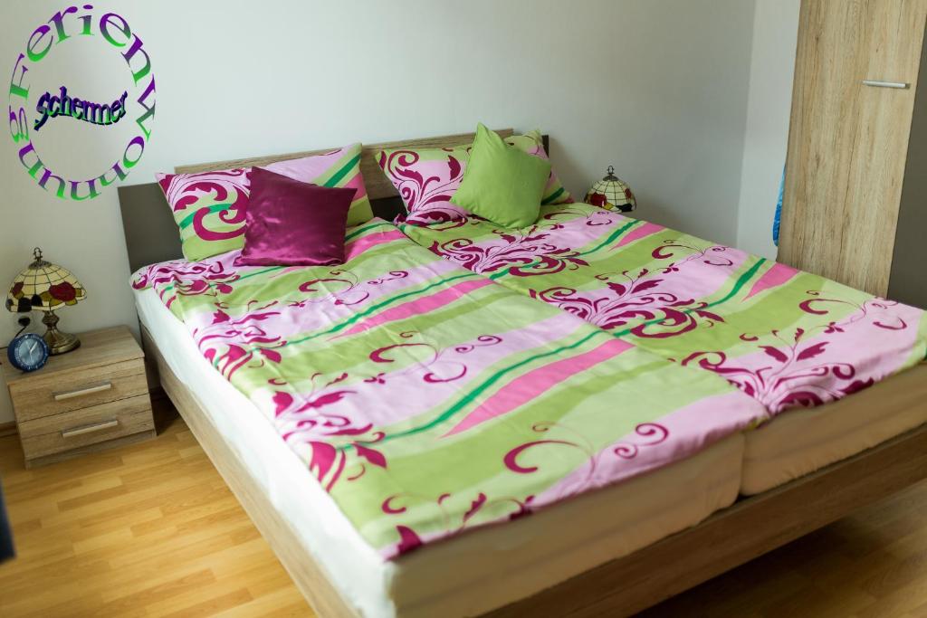 een bed met een roze en groene dekbed en kussens bij Ferienwohnung Schermer in Rinteln