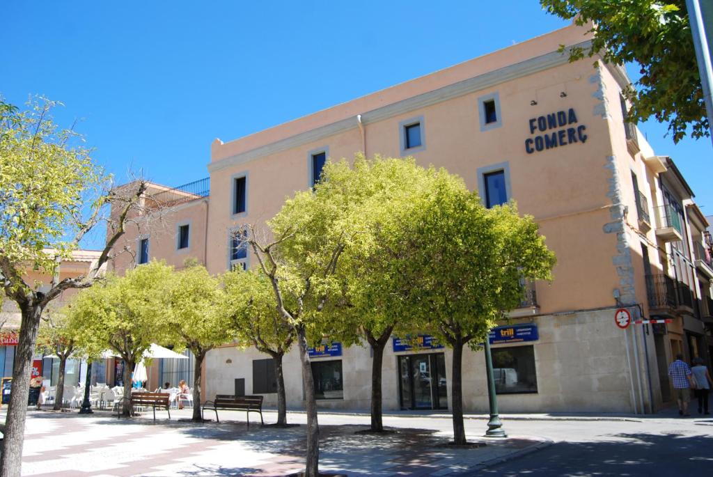 um edifício numa rua com árvores em frente em Apartaments Fonda Comerç em Torroella de Montgrí