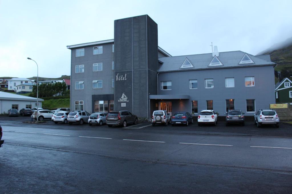 a building with cars parked in a parking lot at North Star Guesthouse Olafsvik in Ólafsvík