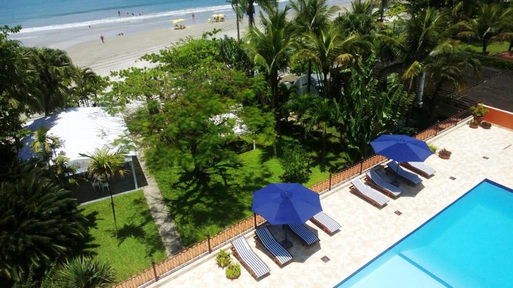 
a beach area with chairs, tables and umbrellas at Hotel Porto Di Mare in Ubatuba
