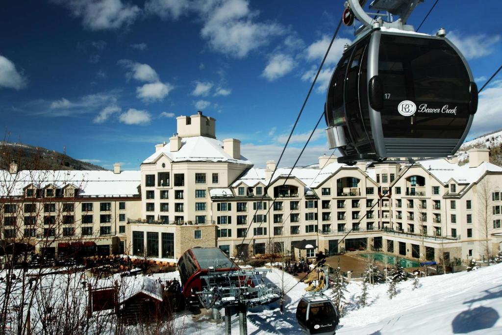 Park Hyatt Beaver Creek Resort and Spa, Vail Valley في بيفر كريك: مصعد الجندول فوق مبنى كبير في الثلج