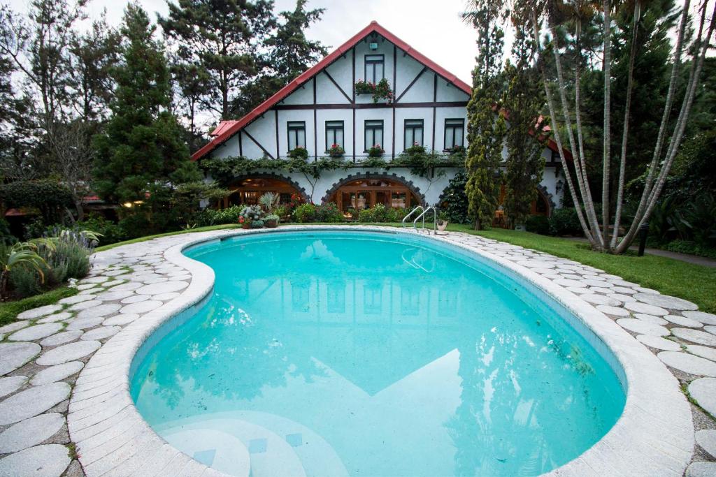 a house with a swimming pool in front of a house at Cabaña Suiza in Guatemala