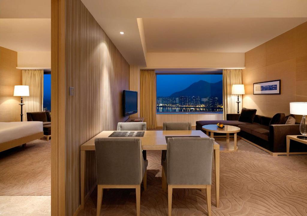 a hotel room with a dining table and a living room at Hyatt Regency Hong Kong, Sha Tin in Hong Kong
