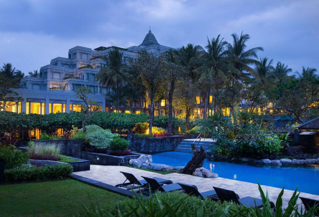 a hotel with chairs and a pool in front of a building at Hyatt Regency Yogyakarta in Yogyakarta