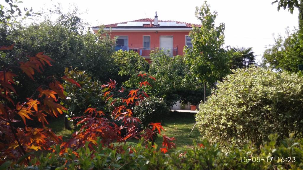 een rood huis achter enkele bomen en struiken bij Il Frutteto in Chieri