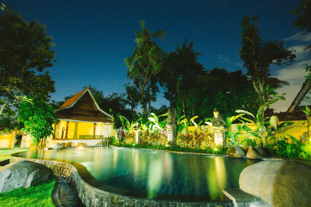 a villa with a swimming pool at night at Baligong Villa in Sukawati