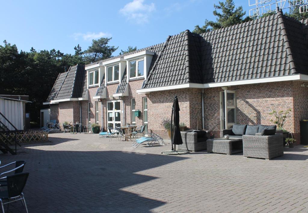 a brick house with a patio and an umbrella at Hotel Studio Bosch Duin Strand in Den Helder