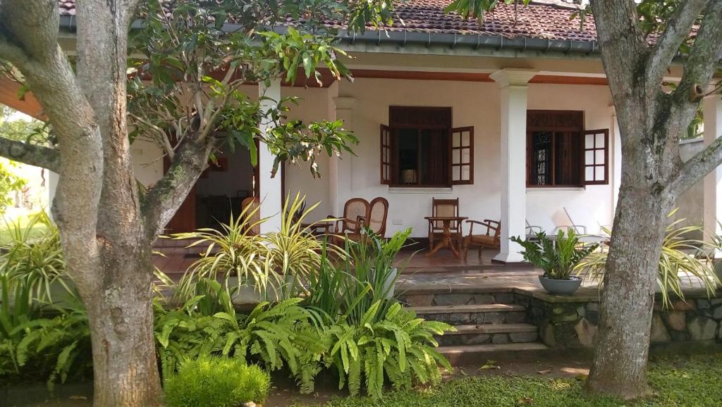 een wit huis met bomen en planten ervoor bij Shalome Villa in Tangalle