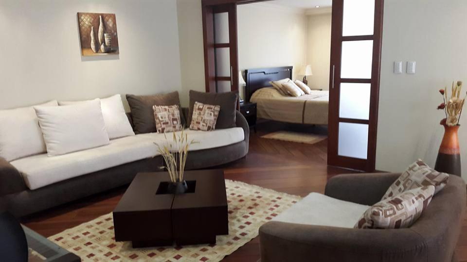 sala de estar con sofá y mesa en Suite AAA, Jacuzzi, WIFI, Cable, Internet, malls, cines, transporte...todo a pocos pasos., en Quito