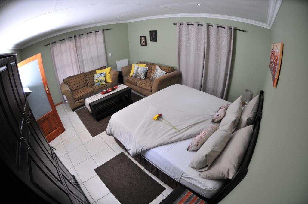 1 dormitorio con 1 cama y sala de estar en Summer Garden Guest House (The Flower Box), en Benoni