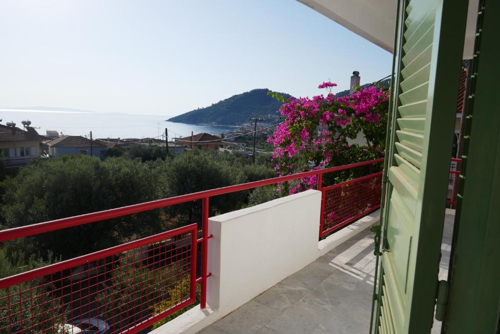 a balcony with a red railing and pink flowers at Tiros Apartments Armonia in Tyros