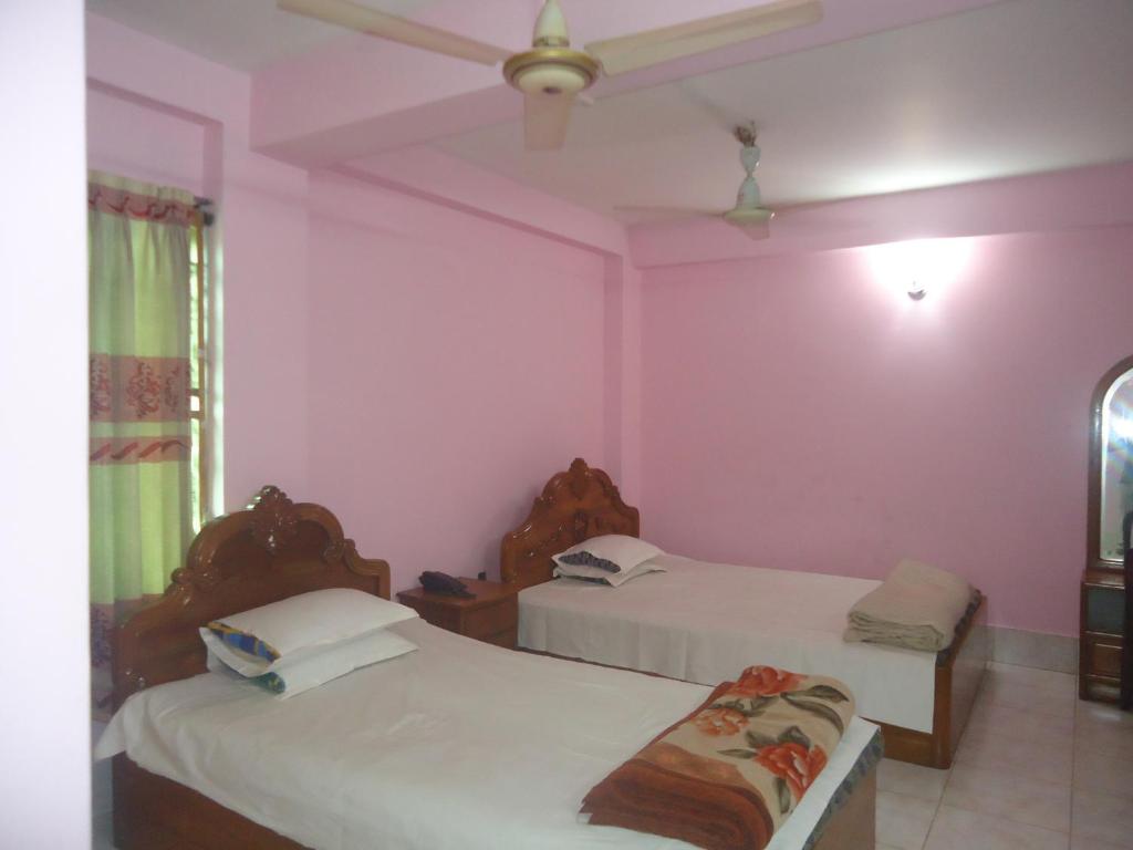 zwei Betten in einem Zimmer mit rosa Wänden in der Unterkunft Hotel Green Castle in Rangamati