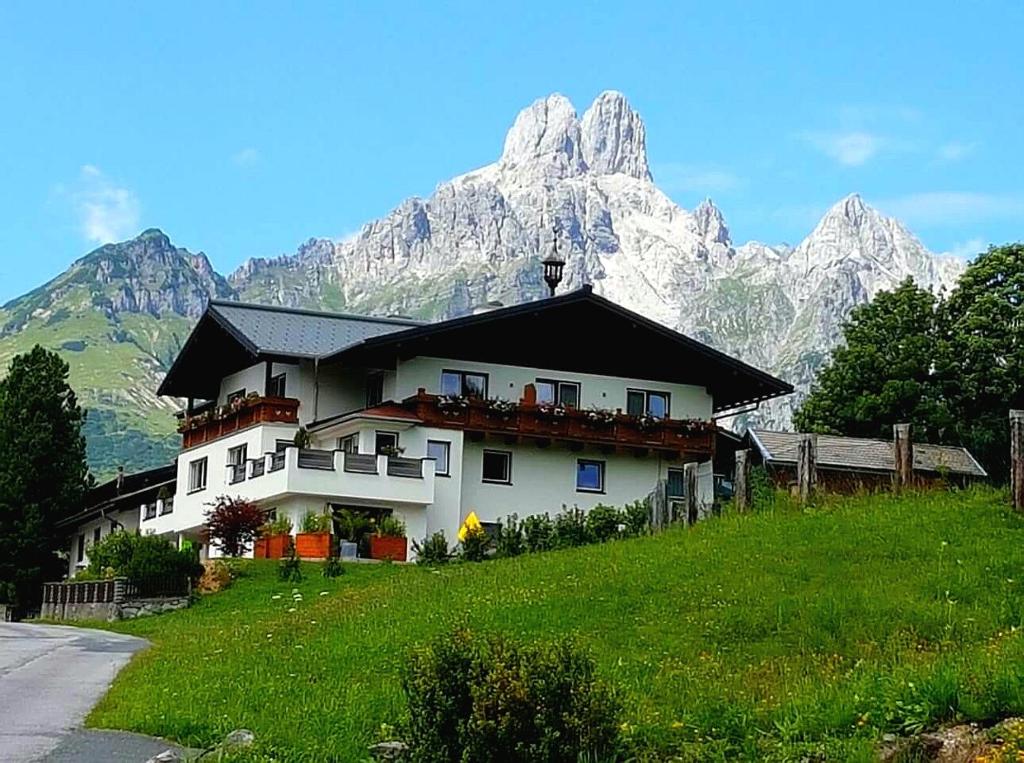 ein Haus auf einem Hügel mit einem Berg im Hintergrund in der Unterkunft Haus Bergfried in Filzmoos