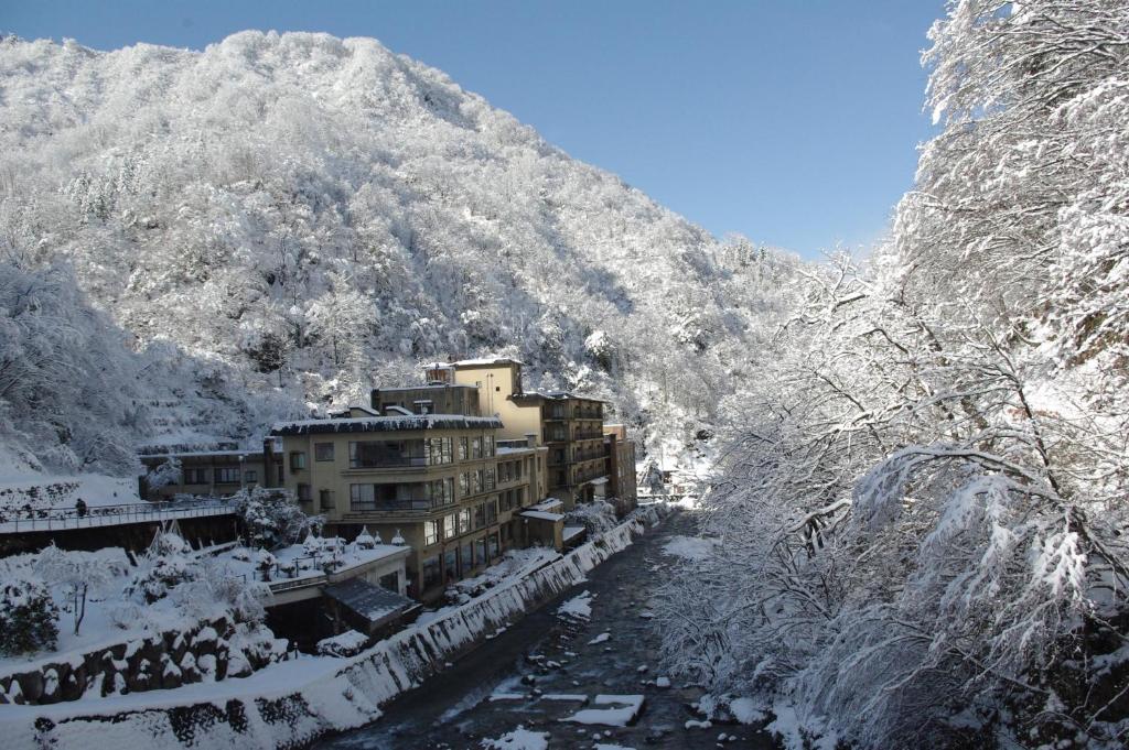 uma cidade coberta de neve em frente a uma montanha em Hotel Ogawa em Asahi